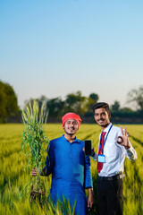 Fototapeta premium Young indian agronomist with farmer at green wheat field