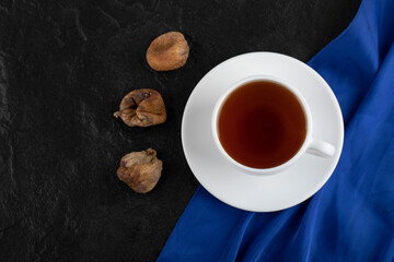 Dried rose petals with a cup of hot tea on a black background