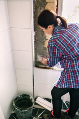 Female bricklayer leveling cement with a trowel to tile the wall