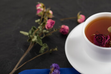 Dried roses with a cup of hot tea on a black background