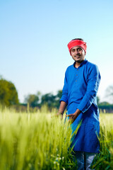 Fototapeta premium Young indian farmer at green wheat field
