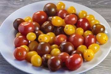 Multicolored tomatoes of different varieties in a dish. Fashionable vegan food.