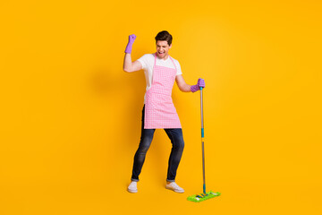 Full size photo of young crazy happy positive smiling man washing floor raise fist in victory isolated on yellow color background
