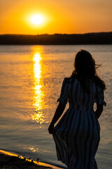 Fototapeta premium Woman standing at the beach on sunset in dress
