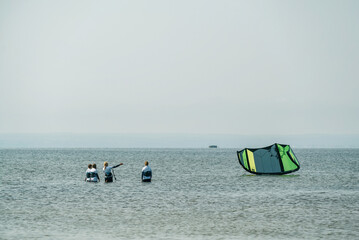 People swim in the sea on a kiteboard or kitesurfing. Summer sport learning how to kitesurf. Kite...