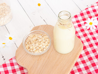 Glass bottle with vegetable oat milk and oat flakes. Lactose-free milk, vegetarianism.