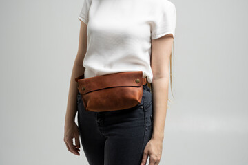 Girl in a white blouse with a leather red handmade bag over her waist. Designer dark brown banana...