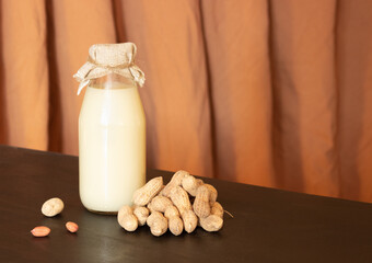 Glass bottle with peanut milk and peanuts in the shell. Lactose-free milk, vegetarianism.