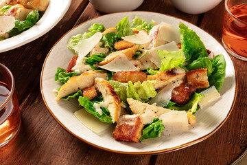 Caesar salad close-up. Grilled chicken breast slices, green romaine salad leaves, croutons and Parmesan, the classic recipe