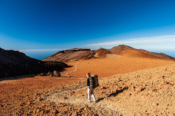 Young woman hiker with backpack trekking near Pico del Teide mountain in El Teide National park....