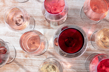 Wine variety. White, rose, and red wine in many glasses, overhead flat lay shot on a wooden background