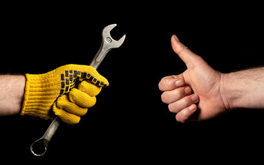 Close-up of people hands, one holds a wrench, and the other shows an ok sign. The concept of...