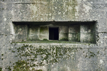 A brutalist cold gritty concrete world war two, ww2, pillbox war bunker gun hole in a defence fortress, in a dirty forgotten woodland in europe. wartime relics and forgotten outpost