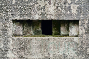 A brutalist cold gritty concrete world war two, ww2, pillbox war bunker gun hole in a defence fortress, in a dirty forgotten woodland in europe. wartime relics and forgotten outpost