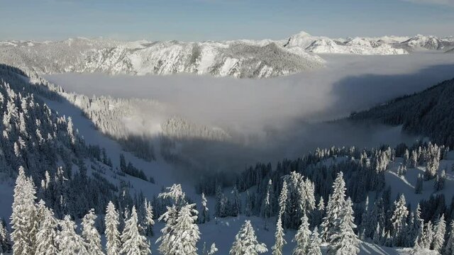 Snow Covered Mountain Valley with Majestic Lowland Fog Backward Aerial
