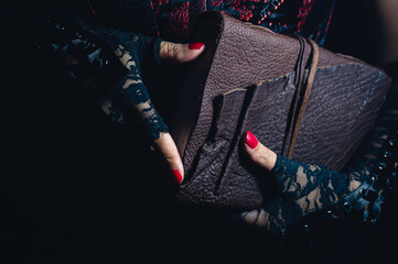 Women wearing black lace gloves holding a brown leather bound tome