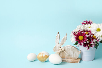 Naklejka na ściany i meble spring flowers with white easter eggs and wooden bunny on blue background, copyspace