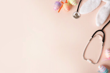 Stethoscope and easter eggs, bunny ears on pink background with a copy space