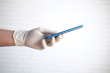 side view of doctor's hand in protective gloves using a smartphone