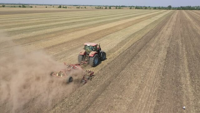 Agricultural work with a tractor. The tractor driver plays the ground with a disc harrow.