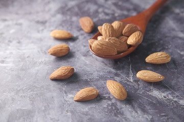 Close up of almond nuts in a spoon on black backgorund 