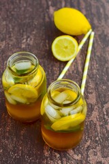 Iced tea with lemon slices and mint leaves on rustic background