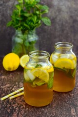 Iced tea with lemon slices and mint leaves on rustic background