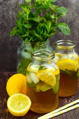 Iced tea with lemon slices and mint leaves on rustic background