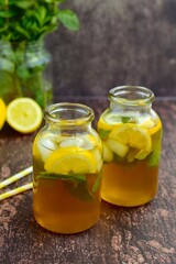 Iced tea with lemon slices and mint leaves on rustic background