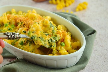 Creamy baked cavatappi pasta with sweet potato, cheddar cheese, peas and spinach garnish with panko crumbs