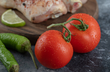 Fresh organic tomatoes and peppers with raw chicken legs