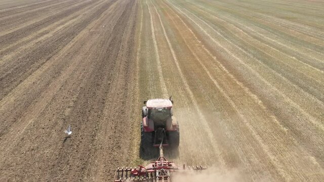 Agricultural work with a tractor. The tractor driver plays the ground with a disc harrow.