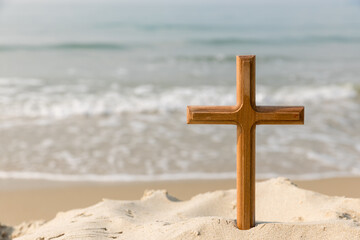 Wooden cross on the beach of the  Sea background. Easter concept. Concept  cross religion symbol in grass over sunset or sunrise sky.