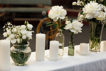 Table setting at wedding reception. Floral compositions with beautiful flowers and greenery, candles on decorated table. Coziness and style. Modern event design. selective focus.