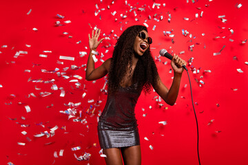 Photo of young afro girl happy smile excited sing song microphone event party fly air confetti...