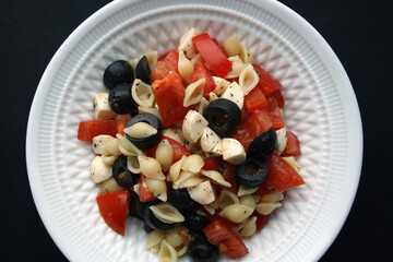 Italian salad with pasta, tomatoes and mozzarella. Culinary background.