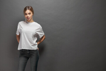 Fototapeta na wymiar Woman wearing white blank t-shirt with space for your logo, mock up or design over gray background