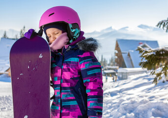 Little cute girl snowboarding at ski resort in sunny winter day. Caucasus Mountains. Portrait of...