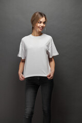 Woman wearing white blank t-shirt with space for your logo, mock up or design over gray background