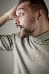 Fototapeta premium Young man with a short beard touches his head in a moment of relaxation 