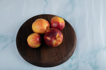 Red and yellow peaches on a wooden board on the table