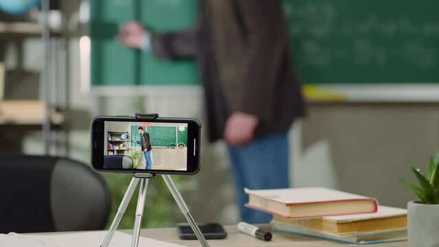 European elementary school male teacher teach math online through webcam in classroom