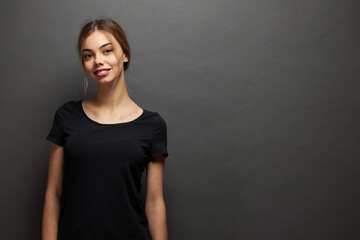 Woman wearing black blank t-shirt with space for your logo, mock up or design in casual urban style over gray background