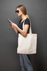 Tote eco bag for mockup is held by a woman over gray texture
