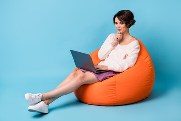 Photo portrait full body view of thinking girl with laptop sitting in orange beanbag chair isolated...