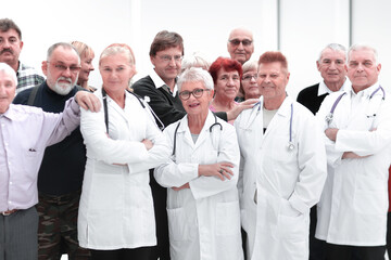 Happy doctors standing in corridor with team at hospital with crossed arms looking at camera