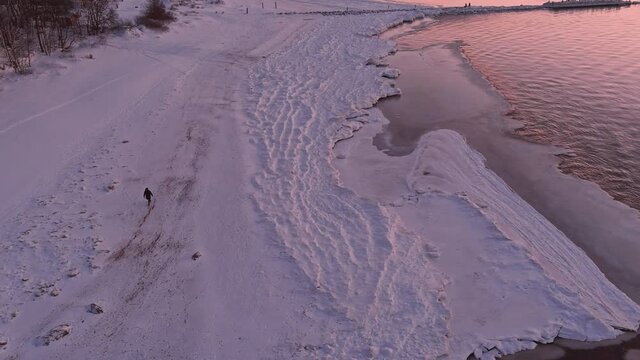 Sunset in a calm sea with frozen seashore. Shot from drone