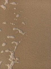 Traces of waves lapping on the sandy beach create beautifully detailed bubbles