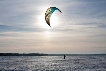 Horizontal outdoor sports photo with a lone man ski kiter skydiving in a strong wind in the winter daytime