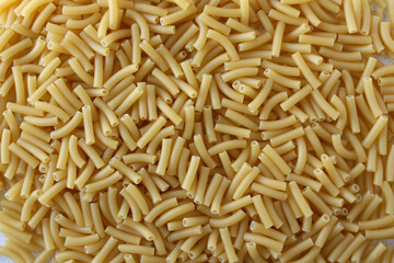 Short Italian penne pasta. Concept - traditional Italian dishes made from wheat. Dry pasta background. View from above.
